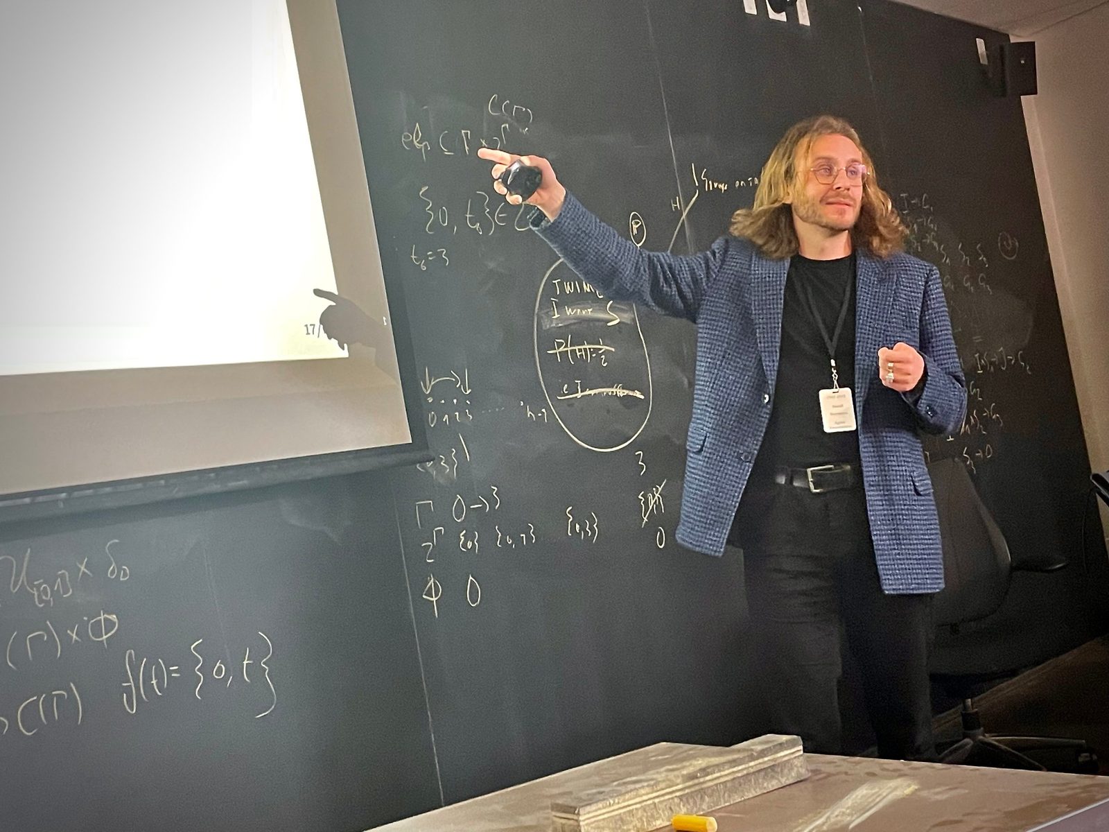 Daniel Herrmann giving a talk at a blackboard